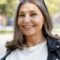 Close up vertical shot of trendy looking middle aged sixty year old Caucasian female enjoying nice walk in park on sunny day, looking at camera with broad carefree happy smile. Style, age and people